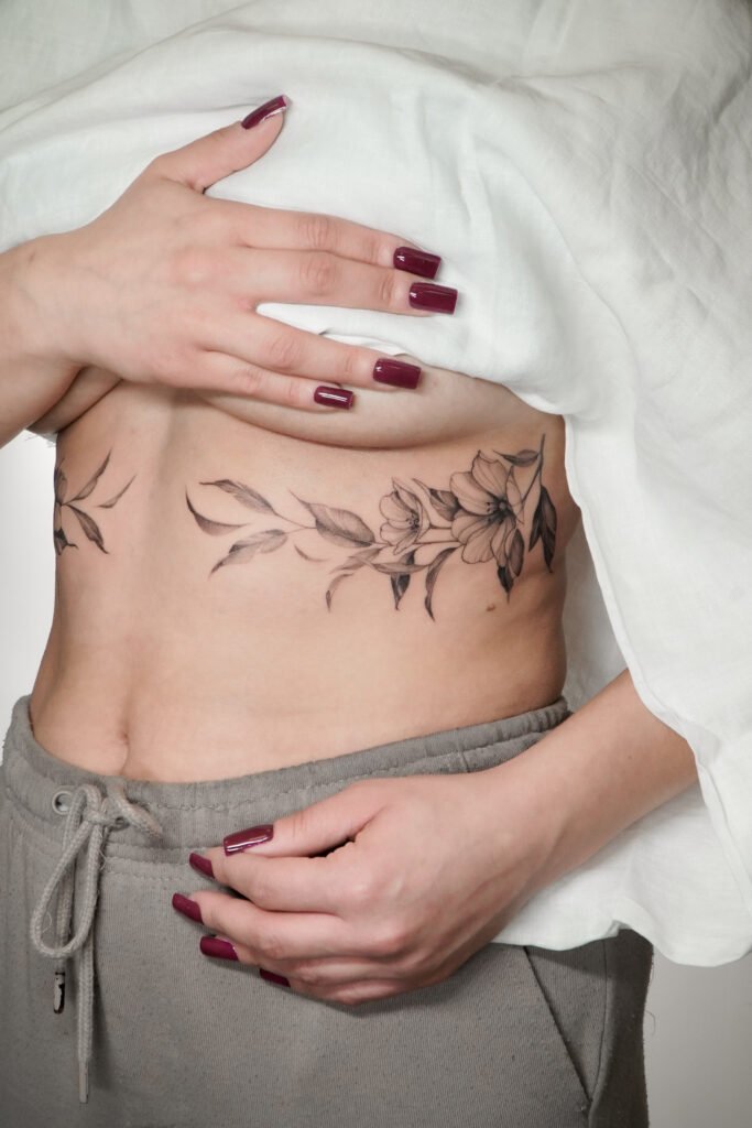 Delikatny czarno-szary tatuaż florystyczny fine line, umieszczony na boku tułowia. Elegancka, subtelna kompozycja botaniczna, stworzona dla osób poszukujących kobiecego, roślinnego motywu o minimalistycznym i wyrafinowanym charakterze. Tatuaż wykonany przez Olgę Sankovą (@olga_sankova_tattoo) w Fineline Tattoo Gallery dla Tattoo Kraków Kolektyw Artystów.