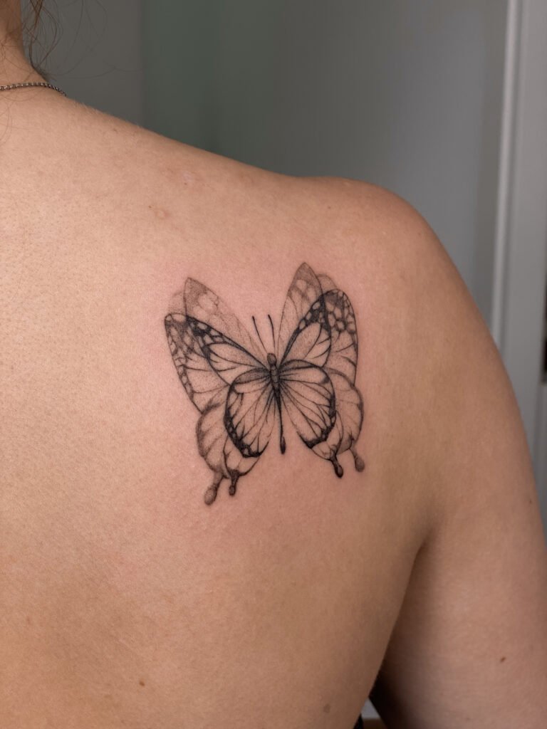 Delikatny tatuaż fine line z motywem motyla, umieszczony na górnej części pleców, wykonany precyzyjną kreską i subtelnym cieniowaniem typu dotwork. Symetryczna, zwiewna kompozycja podkreślająca lekkość i transformację. Tatuaż wykonany przez Yarę (@yaroslavaa.tattoo) w Fineline Tattoo Gallery w Krakowie dla Tattoo Kraków Kolektyw Artystów.